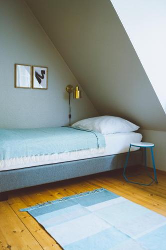 a bed in a attic with a lamp and a rug at Gut Oehe in Maasholm