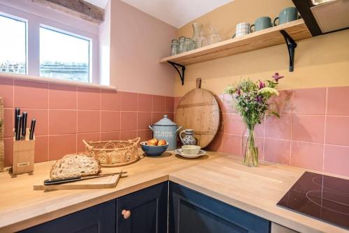 a kitchen with pink tiles and a counter with a vase of flowers at The Stables, Hoo in Woodbridge