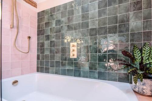 a bath tub in a bathroom with pink tiles at The Stables, Hoo in Woodbridge