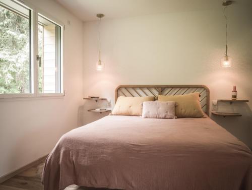 een witte slaapkamer met een groot bed met 2 kussens bij Venez Chez Vous - Chalet de Bredanne - Bord du lac in Doussard