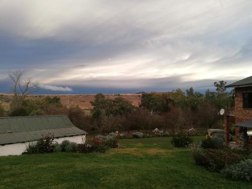 a house in a yard with a field in the background at Sheeprun Farmstay in Maclear