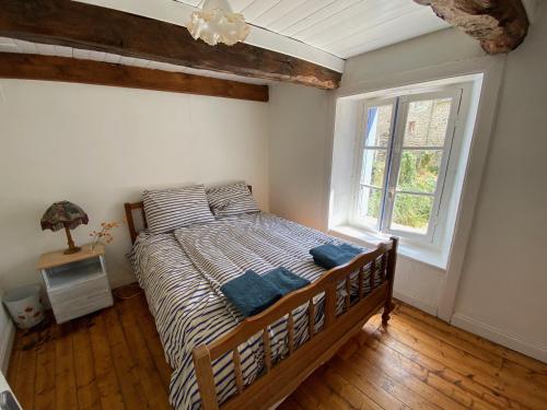sypialnia z łóżkiem w pokoju z oknem w obiekcie Breton stone cottage with a garden near the river w mieście La Vicomté-sur-Rance