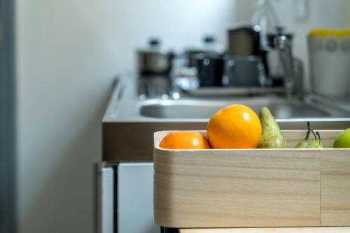 a wooden box filled with oranges and pears in a kitchen at FE The family escape apartment in Woodford Green