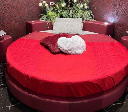 Una cama roja con dos almohadas encima. en DEVILTHON SUITE NETTUNO, en Nettuno