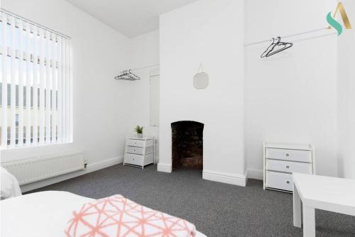 Dormitorio blanco con cama y chimenea en Thornaby Road TSAC en Stockton-on-Tees