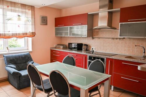 a kitchen with red cabinets and a table and chairs at Rožės Namai B&B in Raseiniai