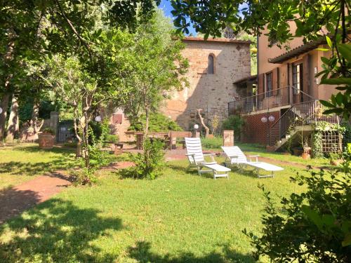 a yard with two white chairs in front of a house at La Villa del Borgo in Massa Marittima
