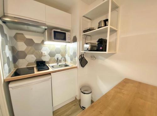 une petite cuisine avec un évier et un micro-ondes dans l'établissement Studio rénové avec Terrasse 100m plage 50m Port, à Mauguio
