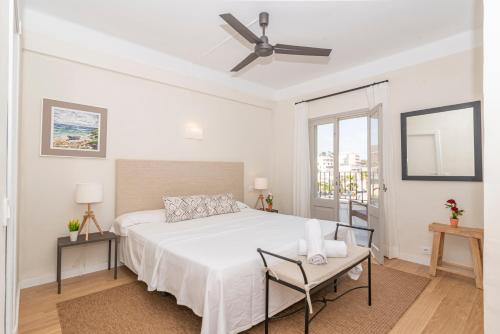 een witte slaapkamer met een bed en een plafondventilator bij Boutique Hotel Oriola in Cala de Sant Vicent