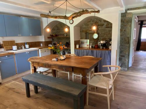 kuchnia z drewnianym stołem i niebieskimi szafkami w obiekcie Breton stone cottage with a garden near the river w mieście La Vicomté-sur-Rance