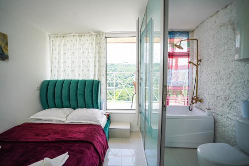 a bedroom with a bed with a green headboard and a window at Sighnaghi Art Hotel in Sighnaghi