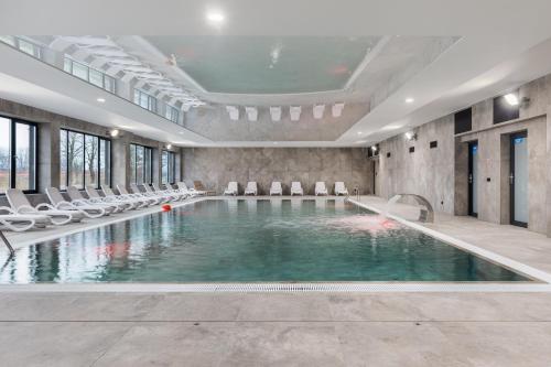 a swimming pool with white chairs and a swimming poolvisor at Wellness Resort Dziwnów Apartments with Parking by Renters Prestige in Dziwnów