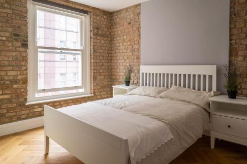 - une chambre avec un lit blanc et un mur en briques dans l'établissement City Air Apartments - HATTON GARDEN - GREAT TRANSPORT LINKS, à Londres