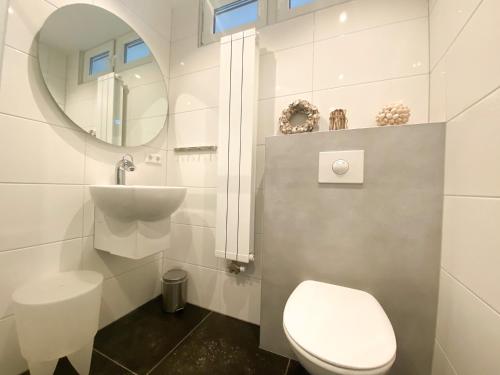 Un baño con inodoro, lavabo y espejo. en Vakantiehuis Zee, Bos & Duin Zoutelande ZO01, en Zoutelande