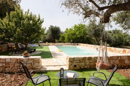 a backyard with a pool with chairs and a table at trullo nonna netta con piscina idromassaggio e area giochi in Ceglie Messapica