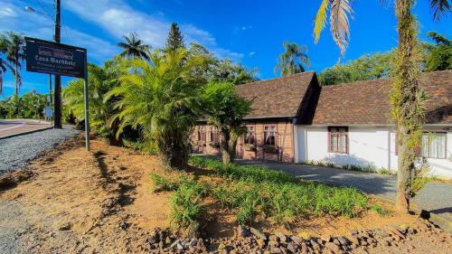 Pousada Casa Wachholz - Rota do Enxaimel في بوميرودي: منزل على جانب الطريق مع أشجار النخيل