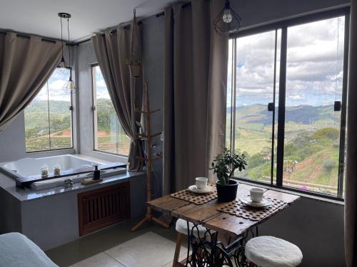 a bathroom with a table and a tub and windows at Estância Shangri-La in Santa Teresa