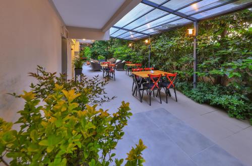 un patio al aire libre con mesas, sillas y plantas en Palmada Hotel, en Sakarya