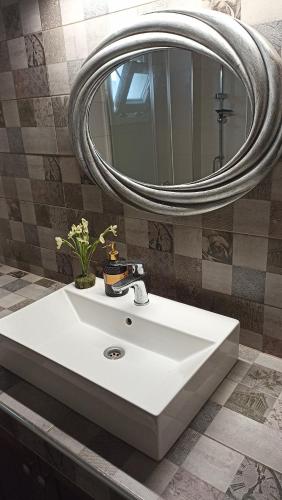 un lavandino bianco in un bagno con specchio di Orestis Cozy Nest a Platamonas