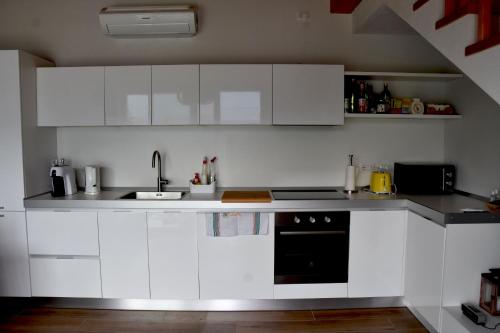 a kitchen with white cabinets and a black oven at Grandin Holidayhouse in Domaso