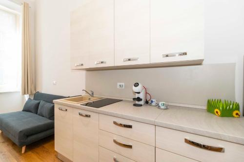 a kitchen with white cabinets and a sink and a couch at Piccolo Principe in Turin