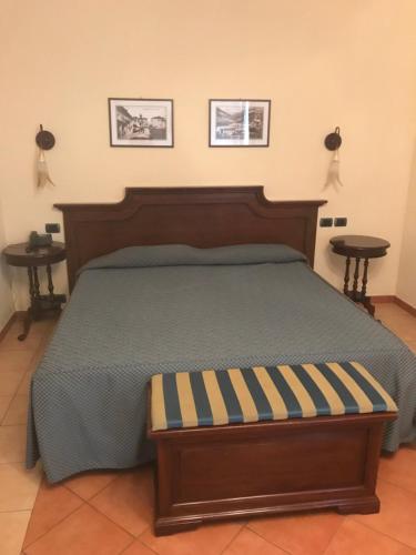 a bedroom with a bed with a wooden headboard and two tables at Hotel Barolo in Barolo