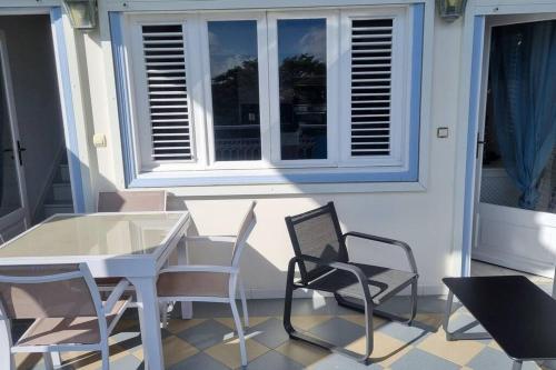 d'une terrasse avec une table, des chaises et une fenêtre. dans l'établissement La Mangotine - Duplex à Saint François avec piscine, à Saint-François