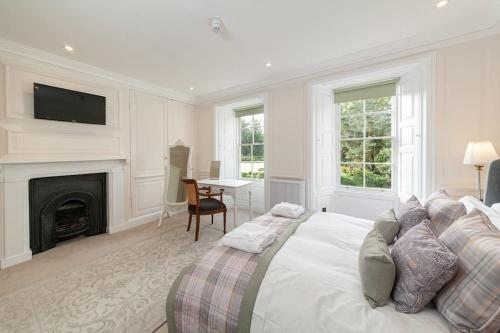 Dormitorio blanco con cama y chimenea en Beautiful Grade II Listed Apartments Sleeping 20, en Hexham