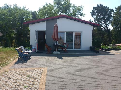 um pequeno edifício branco com um pátio e uma mesa em Pokoje Gościnne Malinówka em Jastrzębia Góra