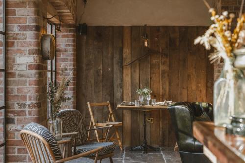 a room with chairs and a table and a brick wall at Outbuildings Dorset in Bridport