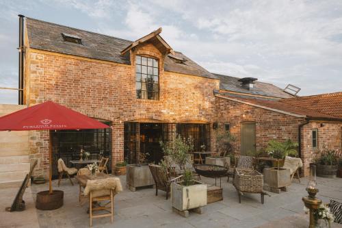 een bakstenen gebouw met een patio met tafels en stoelen bij Outbuildings Dorset in Bridport