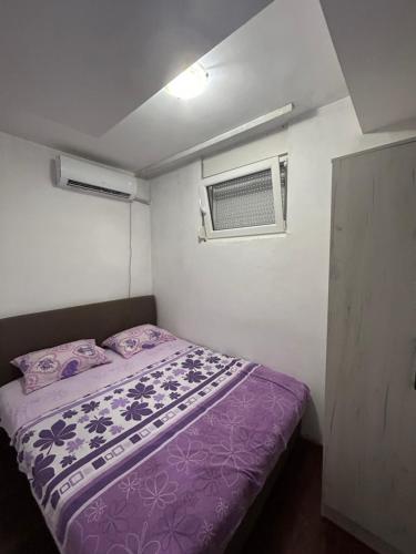 una piccola camera con letto viola e finestra di Apartment Sara a Podgorica