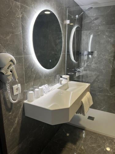 ein Badezimmer mit einem weißen Waschbecken und einem Spiegel in der Unterkunft Hotel 4 Estações in Fátima