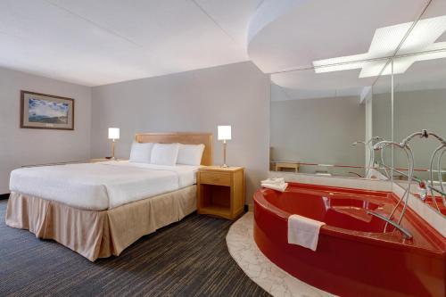 a hotel room with a bed and a bath tub at Days Inn by Wyndham Niagara Falls Near The Falls in Niagara Falls