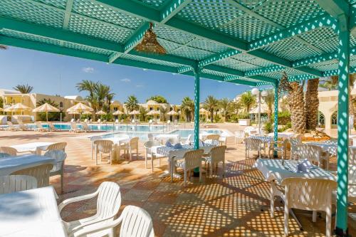 a patio with tables and chairs and a pool at Hotel Venice Beach- Families and Couples Only in Triffa