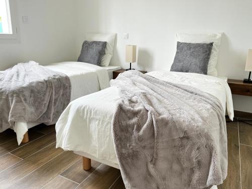 a bedroom with two beds with white blankets on them at Villa Les Romarins in Vallon-Pont-dʼArc