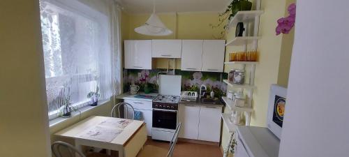 a kitchen with white cabinets and a stove and a table at Ruses14 in Rīga