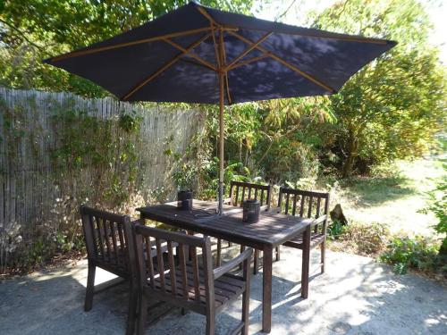 une table en bois avec un parasol et deux chaises dans l'établissement La Maison du Berger de La Chassagne, à Ronnet
