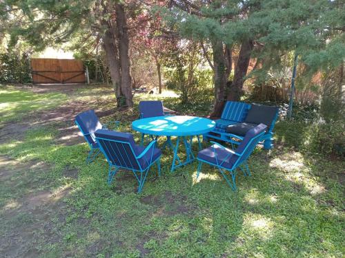 a blue table and four chairs in the grass at Cabaña Pedemonte in Vistalba