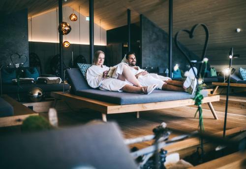 a couple sitting on a couch reading a book at Wellnesshotel Warther Hof in Warth am Arlberg