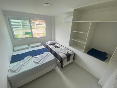 ein kleines Zimmer mit 2 Betten und einem Fenster in der Unterkunft SOLAR DE PORTO RICO "Aptms" P GALINHAS in Porto De Galinhas