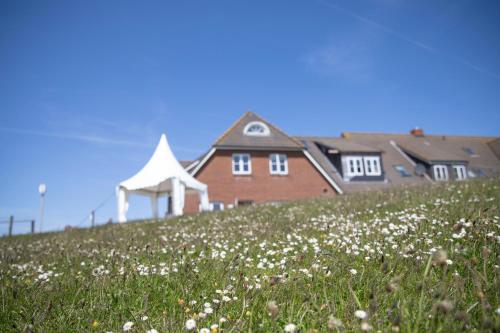 a house on a hill with a field of flowers at Anker's Hörn - Hotel & Restaurant auf der Hallig Langeness in Langeneß