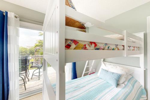Ce lit superposé blanc se trouve dans un dortoir doté d'un balcon. dans l'établissement Aqua Vista, à Surf City