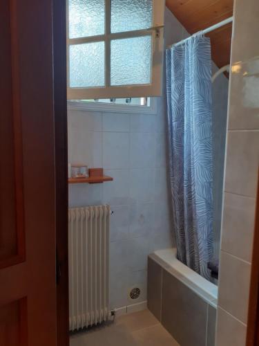 a bathroom with a window and a tub and a radiator at Au Bosquet, chambre et salle de bains avec petit déjeuner à 600 m du centre dans un cadre calme et verdoyant in Salies-de-Béarn