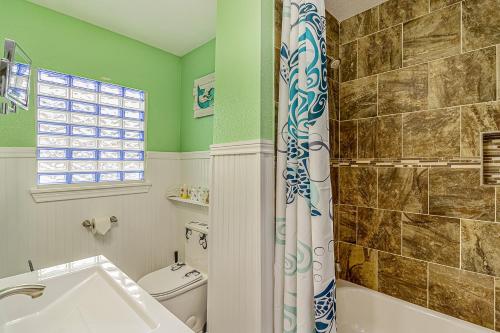 a bathroom with a tub and a toilet and a shower at Jamaican Waves in Galveston
