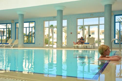 a young child laying in a swimming pool at Hotel Venice Beach- Families and Couples Only in Triffa