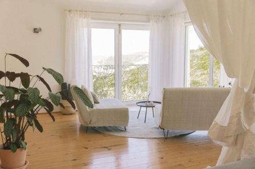 uma sala de estar com um sofá, uma cadeira e uma janela em Sãone Guesthouse & Coworking na Ericeira