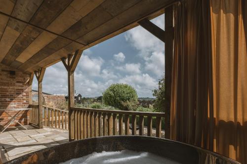 a bath tub on a balcony with a view at Outbuildings Dorset in Bridport