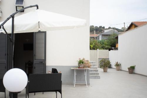 un patio blanco con mesa y sombrilla en Affittacamere Parisi, en Villaggio Mosè