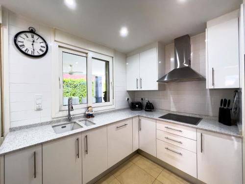 a kitchen with white cabinets and a clock on the wall at Villa Sam 3 Bedroom Villa in Mar Menor Golf in Murcia